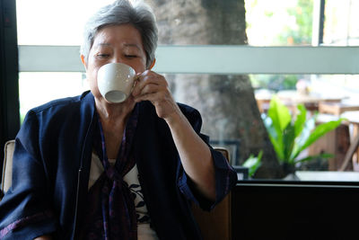 Senior woman drinking coffee while siting at cafe