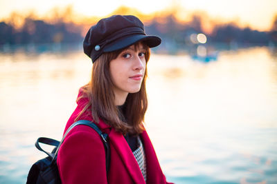 Portrait of beautiful young woman standing against lake