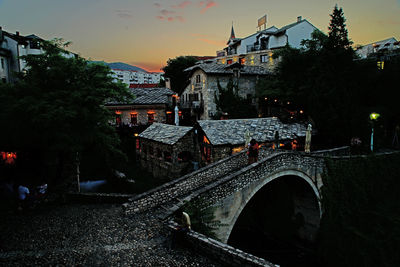 Illuminated buildings against sky at sunset