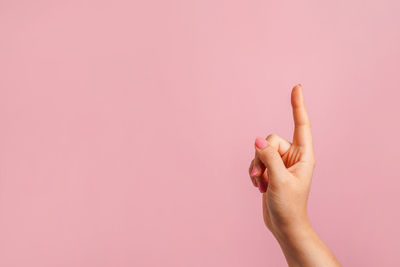 Cropped hand of woman against green background