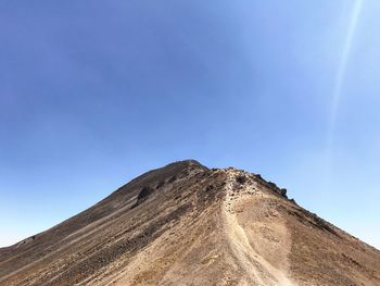 Low angle view of mountain against blue sky