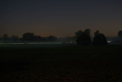 Silhouette trees on field against sky during sunset