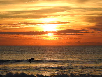 Scenic view of sea against cloudy sky during sunset