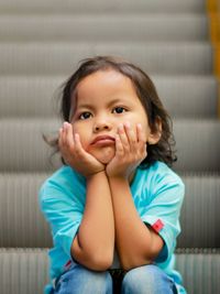 Portrait of cute girl sitting on floor at home