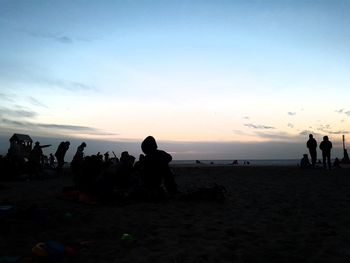 Silhouette people on beach against sky during sunset