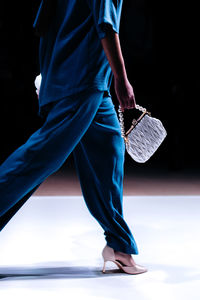 Small white handbag clutch in woman's hand, blue blouse and pants. women's stylish modern fashion