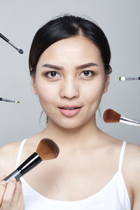 Portrait of woman applying make-up against white background