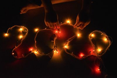 Low angle view of hands holding illuminated fire at night