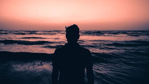 Silhouette man standing at beach during sunset