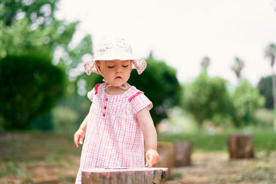 Cute girl wearing hat standing against plants