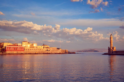 View of buildings by sea against cloudy sky