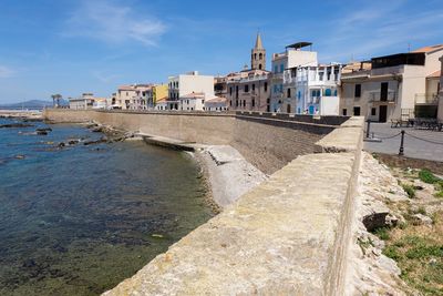 Buildings by sea against sky in city porto torres