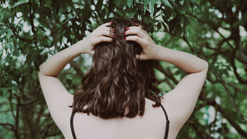 Cropped hand of woman with eyes closed against trees