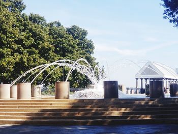 Fountain by swimming pool against sky