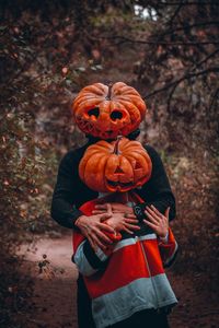 Full length of a man holding pumpkin while standing on tree during autumn