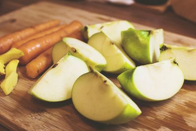 Close-up of granny smith apple slices with carrots on cutting board
