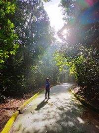 Rear view of woman walking on road amidst trees