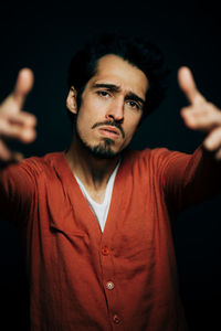 Portrait of young man gesturing against black background