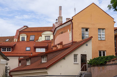 Vintage roofs of houses with windows, balconies and ventilation pipes against sky in old town