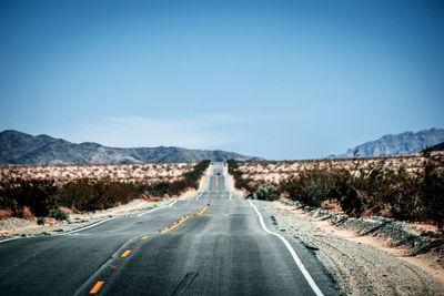 Empty road amidst landscape against sky