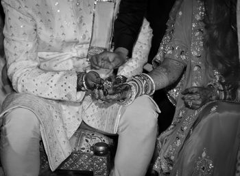 Midsection of bridegroom sitting in traditional clothing on their marriage 