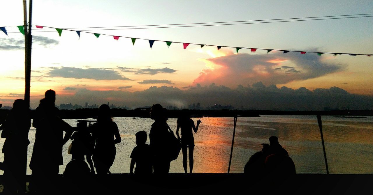 SILHOUETTE PEOPLE AGAINST RIVER AGAINST SKY DURING SUNSET