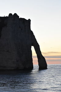 Rock formation in sea against clear sky