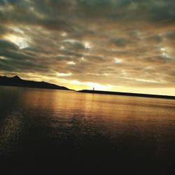 Scenic view of sea against cloudy sky during sunset