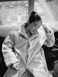 Portrait of young woman sitting on bed at home