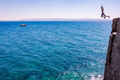 Man jumping off cliff into sea