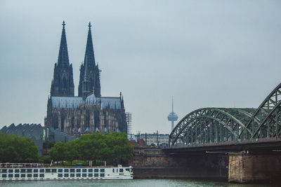 Arch bridge over river by buildings against sky in city