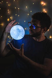 Young man holding camera at night