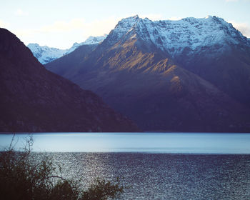 Scenic view of lake wakatipu by snowcapped mountains against sky.  queenstown, new zealand.