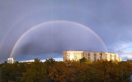 Low angle view of rainbow over city against sky
