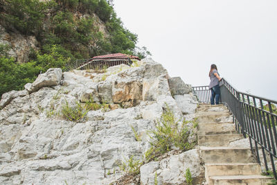 Man standing on staircase by rocks