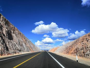 Road leading towards mountains against sky