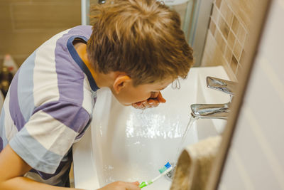 Close-up of boy brushing teeth at bathroom