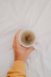 Directly above shot of hand holding coffee cup