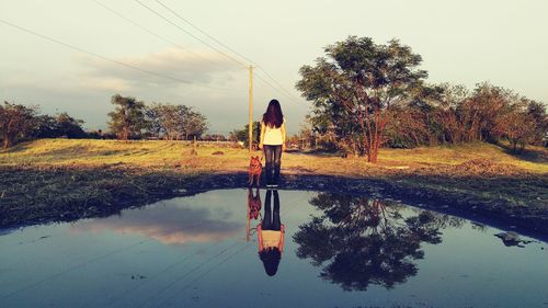 Face covered woman by dog reflecting on pond