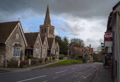 Road by buildings against sky in city