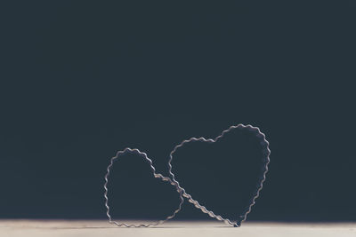 Close-up of heart shape on table against black background