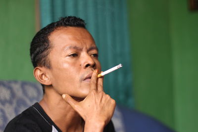 Mid adult man smoking cigarette at home
