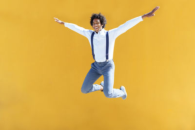 Portrait of man jumping against yellow background