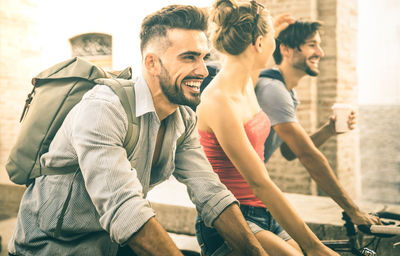 Cheerful friends riding bicycles on road