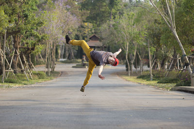 Rear view of man running on road against trees