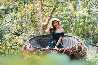 Portrait of smiling woman sitting in wicker container