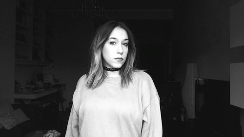 Portrait of young woman standing in living room at home