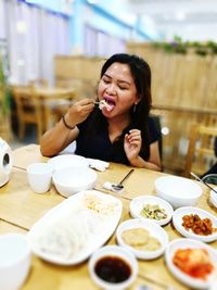 Young woman eating food on table