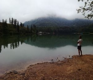 Man standing by lake against sky