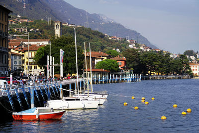 Sailboats moored in harbor by town